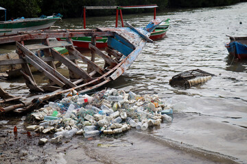 Fishermen's nets' waste lies discarded near a damaged wooden boat, creating an environmental...
