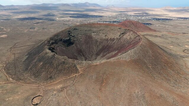 Aerial clip of the dramatic Volcan Calderon Hondo volcano with deep crater Corralejo and Lajares Fuerteventura Canary Islands Spain