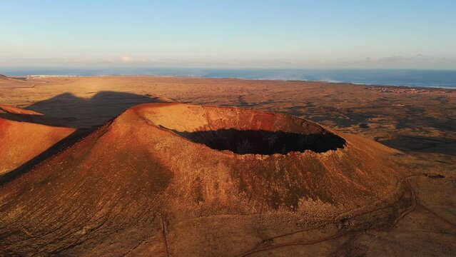 Aerial clip of the dramatic Volcan Calderon Hondo volcano with deep crater Corralejo and Lajares Fuerteventura Canary Islands Spain