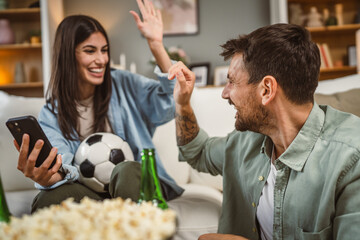 couple watch football match together on mobile phone at home