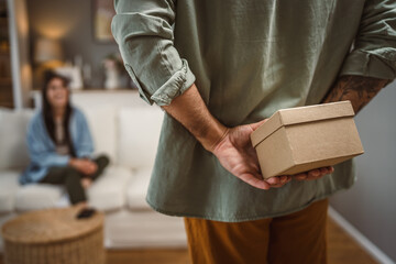 Boyfriend hide behind his back birthday present for his girlfriend