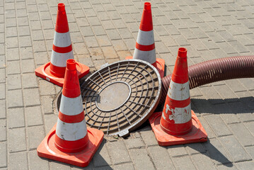 An open sewer manhole on a city street. Repair of city sewerage and drainage systems. Work of public utilities. Repair