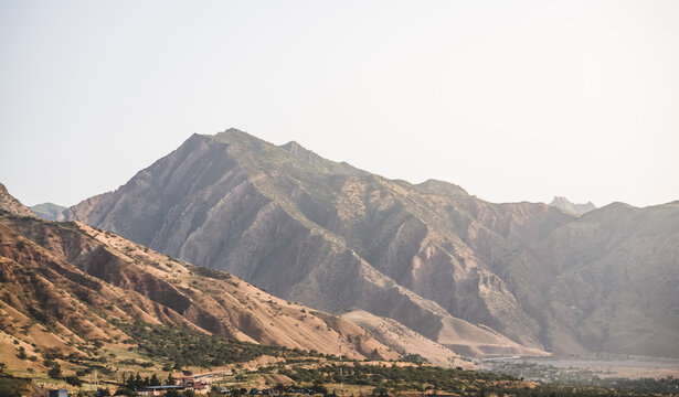 Texture of a rocky mountain range with rocky cliffs and vegetation in the morning at dawn in the mountains of Tajikistan