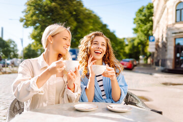 Friendship concept. Two girlfriends women eating breakfast in city cafe together while gossiping and spending free time.