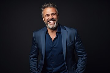 Obraz premium Portrait of a handsome mature man laughing while standing against black background