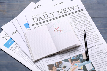 Newspapers with notebook and pen on blue wooden background