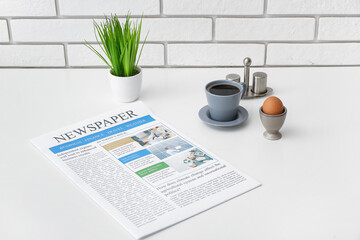 Newspaper with cup of coffee and egg on white table