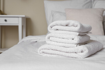 Stack of clean towels on bed in room, closeup