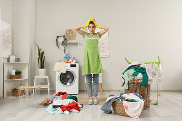 Shocked young woman with dirty laundry near washing machine at home