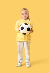 Cute little girl with soccer ball on yellow background