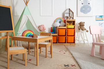 Interior of light playroom with toys, teepee and chalkboard in kindergarten