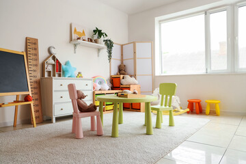 Interior of light playroom with toys and chalkboard in kindergarten