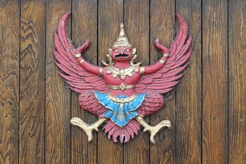 Obraz premium A vintage garuda statue on wooden fence background. 