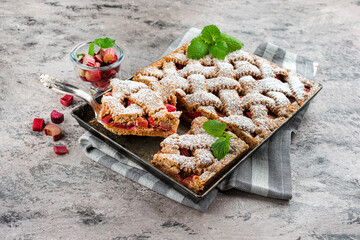 Traditional rhubarb sheet cake with spelt flour served as close-up on a rustic backing sheet