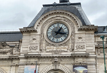 A large clock on a building with the words Paris Orleans written on it
