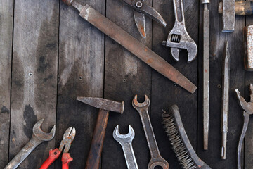 Old work tools on a plank wooden background, top view. Hammers, flat file, tin snips, brush, adjustable wrench and wrench. Hand tool. Builder's Day or Father's Day. Construction and renovation concept