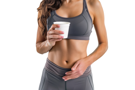 A woman in gray sportswear holds a cup of yogurt, showcasing a healthy lifestyle and fitness routine. The minimalist white background focuses attention on the subject. - Powered by Adobe