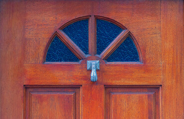 Detalle de puerta de madera labrada y barnizada, con tragaluz de vidrio y aldaba © Iván Serrano