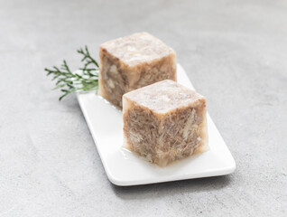 Jellied Meat in the shape of a cube. On a serving plate