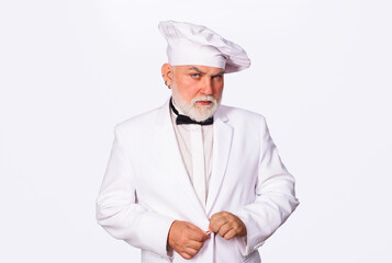 Portrait of serious chef in uniform. Bearded cook or baker man in kitchen restaurant and hotel. Confident male cook in white uniform and chef hat. Professional culinary, cooking and food preparation.