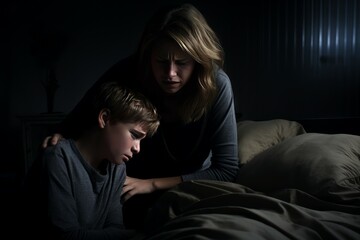 Obraz premium Caring mother consoles her young son in a dimly lit bedroom, providing comfort during a time of distress
