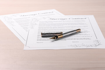 Marriage contracts and pen on light wooden table