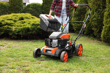 Obraz premium Woman with modern lawn mower in garden, closeup