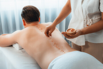 Blissful man customer having exfoliation treatment in luxury spa salon with warmth candle light...