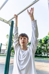 Fototapeta premium Young Man Hanging On Pull Up Bar At Outdoor Gym