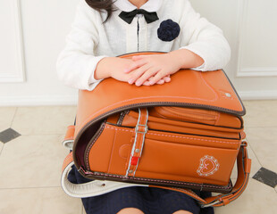 茶色のランドセルを膝にのせて座る女の子