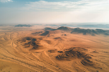 Fototapeta premium Aerial view of a desert landscape from a drone perspective, featuring rolling sand dunes and distant mountains, perfect for a nature-inspired wallpaper