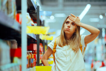 Stressed Woman Checking Inflated Prices in a Supermarket. Unhappy hypermarket shopper finding the...