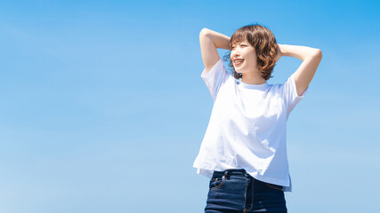 夏の青空と白いTシャツを着た笑顔の女性