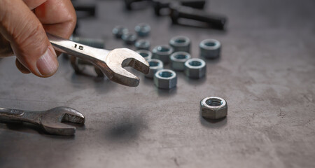 Fototapeta premium Mechanic hand holding socket wrench on steel work bench