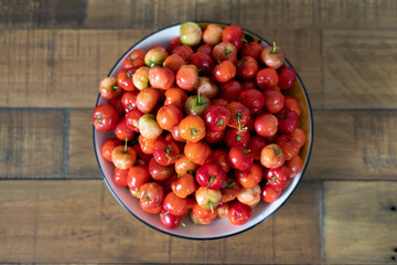Bowl of fresh cherry tomatoes and ripe cranberries on white background
