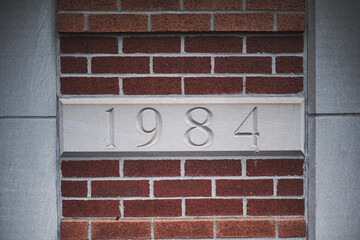 Fototapeta premium Stone plaque with 1984 engraving in brick wall