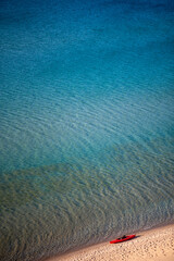 blue water and sand with red boat 