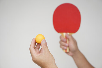 Selective focus on the orange ball on hand with serving table tennis racket. Concept, sport equipment. Exercise or workout tool. Competitive game sport. Playing Ping pong            