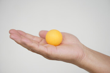Hand holding orange table tennis ball or Ping pong ball, isolated on white background. concept, sport equipment. Exercise and workout tool. Competitive game sport.        