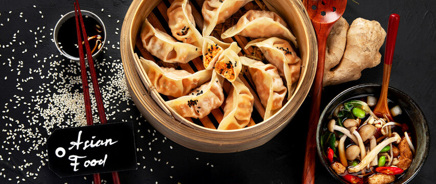 Asian traditional cooked food. Damplings, shrimps and mushrooms soup on black background.Asian traditional cooked food. Damplings, shrimps and mushrooms soup on black background