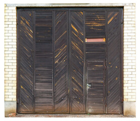 Old large wooden gate in a yellow brick wall isolated