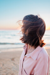Summer mood. girl on the beach. happy young girl in a pink shirt and swimsuit resting on the beach. Happy woman. the girl is standing on the beach. .