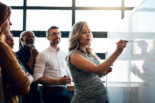 Office, pregnant woman and writing in whiteboard on workshop for planning and idea as project manager. Leader, teamwork and collaboration as employees with mission, solution and strategy for business