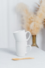 Close-up of white coffee cups on table in a bright kitchen