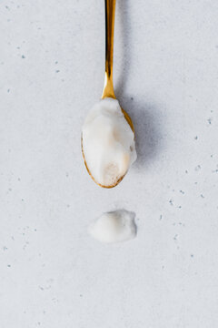 Close-up of a golden tea spoon filled with milk foam