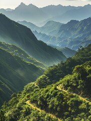 Obraz premium Scenic mountain valley with lush green hills and layered mountain ranges in the background. The picturesque landscape features misty ridges and a serene atmosphere.