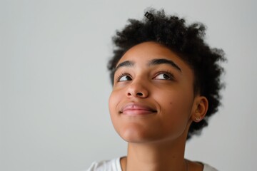 A young woman with a short afro is smiling and looking up at the camera