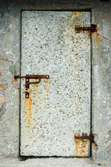 The concrete door is closed. Rusty curtains and lock. Constipation.