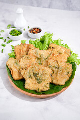 Fried Tempe or Tempe Mendoan served on a plate with spicy sambal and lettuce. Tempe Mendoan is traditional Indonesian Food made from tempeh with flour and spring onions.
