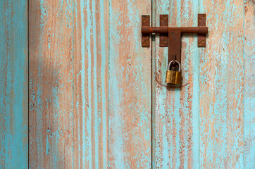 closed blue brown vintage wooden door or close old peeling cyan paint wood window or wall with rusty iron door latch and lock for home retro decor and architecture interior exterior background texture